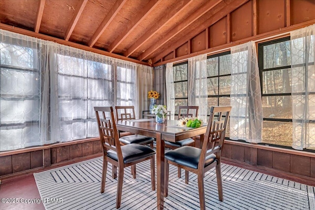 sunroom / solarium with vaulted ceiling, outdoor dining space, plenty of natural light, and wood walls