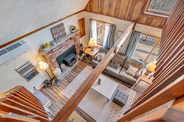 living area with a fireplace, wooden walls, wood finished floors, and vaulted ceiling