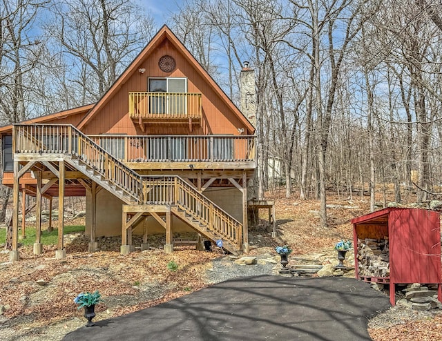 view of front of property featuring a wooden deck, a chimney, and stairs