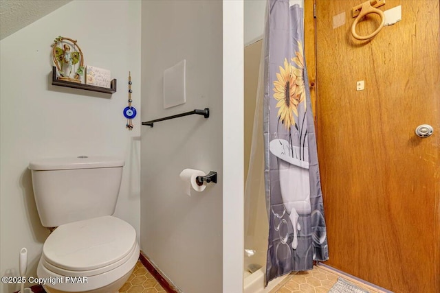 bathroom with toilet, curtained shower, and baseboards