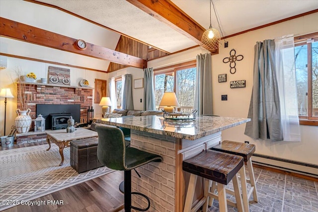 kitchen with ornamental molding, a healthy amount of sunlight, vaulted ceiling with beams, and a breakfast bar area