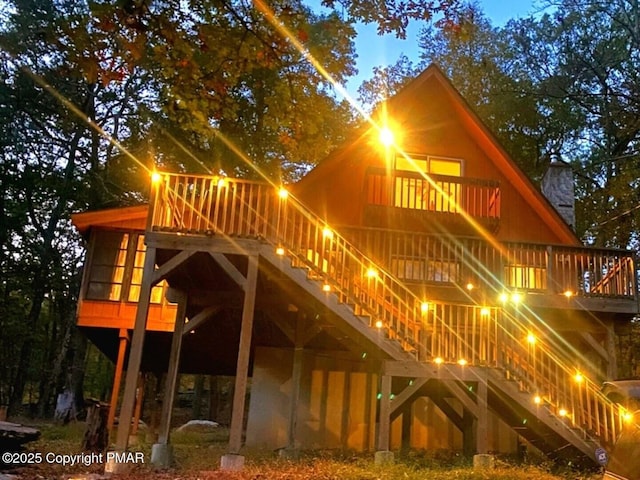 rear view of house featuring a chimney, stairs, and a deck