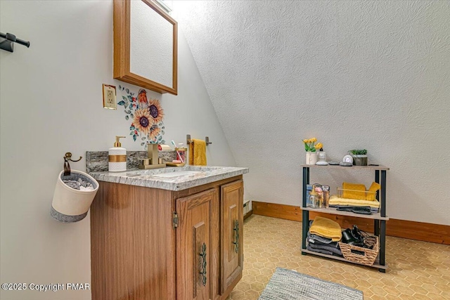 bathroom featuring lofted ceiling, vanity, and baseboards