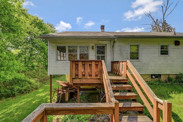 back of property with a chimney, a yard, and a wooden deck