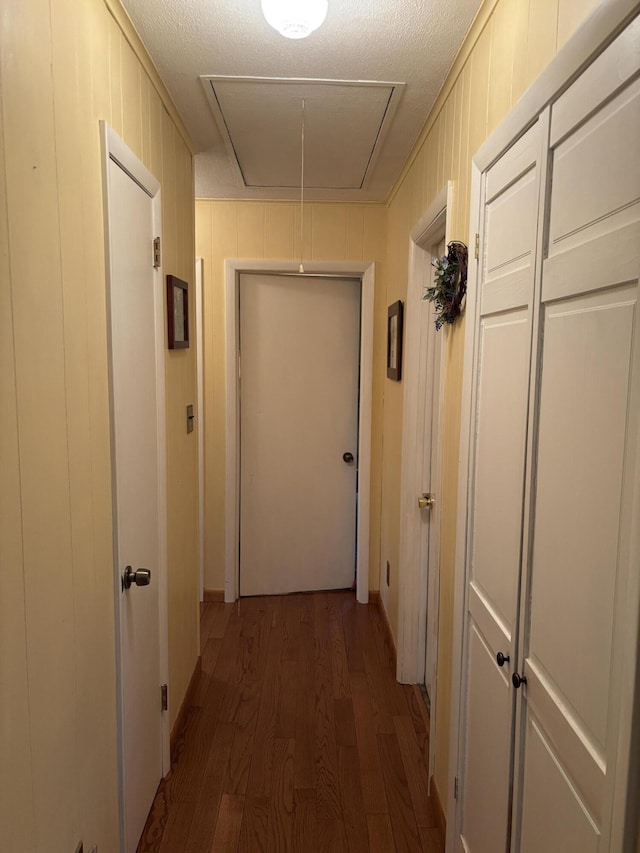 hall featuring a textured ceiling, wood finished floors, and attic access