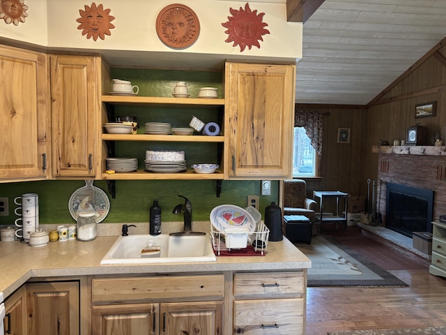 kitchen with a sink, wood finished floors, vaulted ceiling, and light countertops