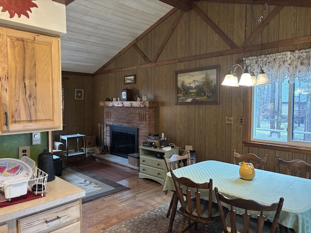 dining room with a fireplace, wood walls, wooden ceiling, vaulted ceiling, and dark wood-style floors
