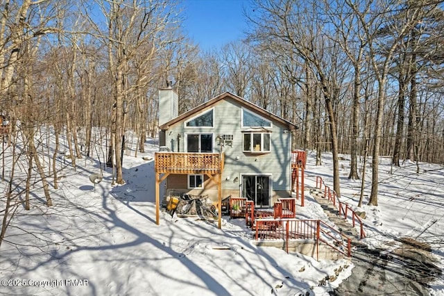 snow covered rear of property featuring a wooden deck