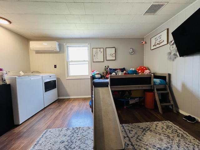 laundry room with an AC wall unit, visible vents, baseboards, separate washer and dryer, and wood finished floors