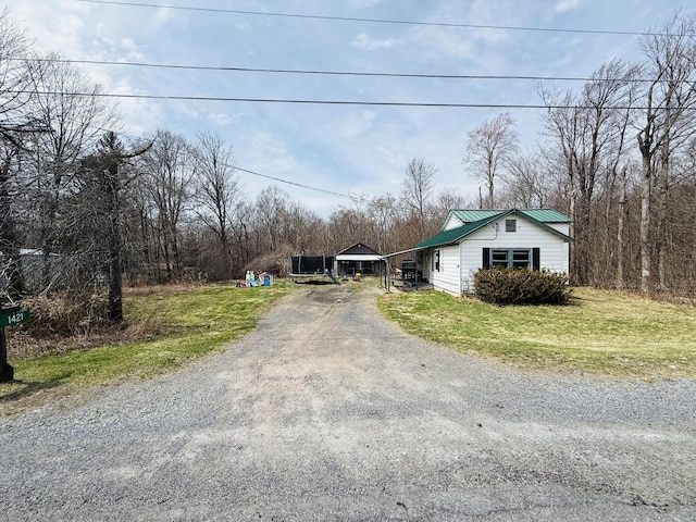 exterior space with dirt driveway, a front lawn, and metal roof