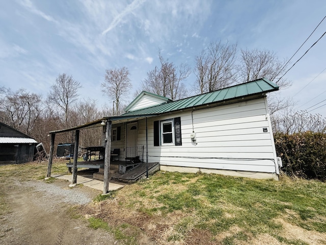 view of front of home with a porch, a front lawn, and metal roof