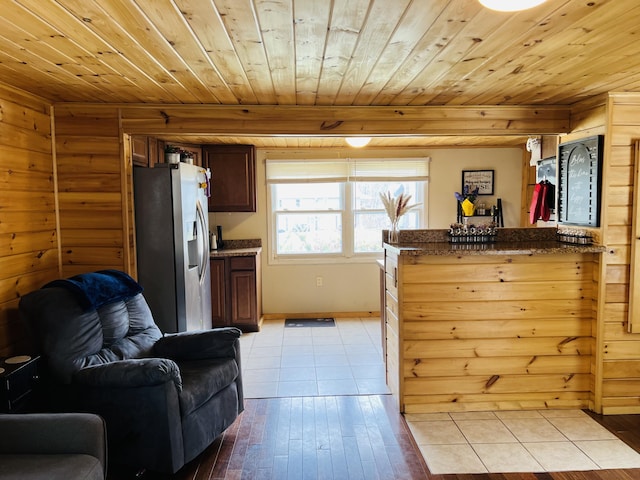 interior space with open floor plan, stainless steel fridge, wood ceiling, and light tile patterned floors