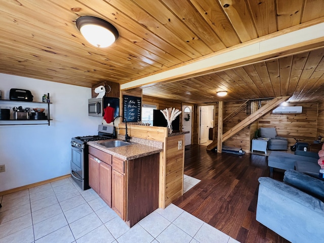 kitchen with stainless steel appliances, a sink, open floor plan, wooden walls, and wooden ceiling