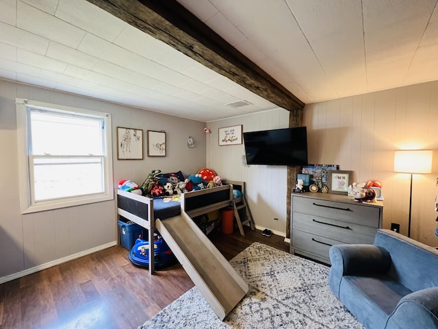 bedroom with baseboards, beam ceiling, and wood finished floors