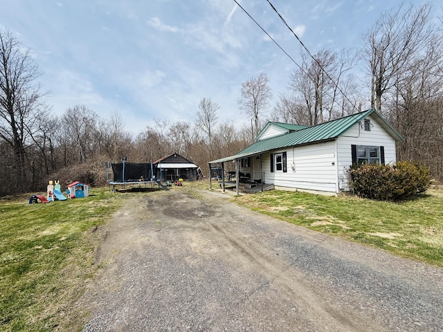 view of front of house with metal roof, covered porch, a trampoline, and a front yard