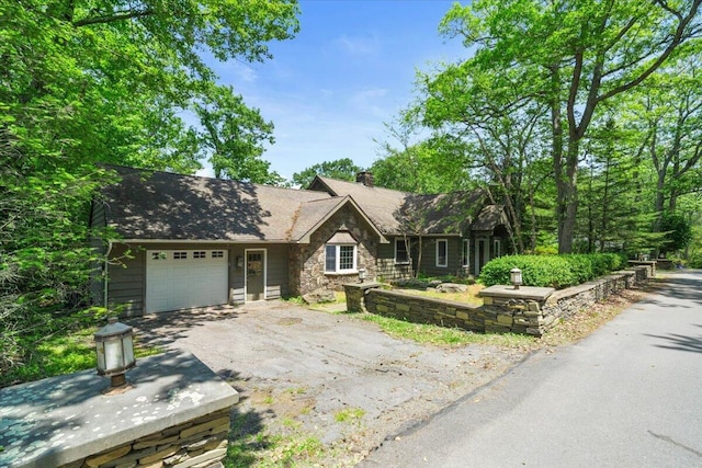2135 Laurel Rd, Buck Hill Falls, PA 18323 - view of front of house featuring stone siding, an attached garage, asphalt driveway, and a chimney