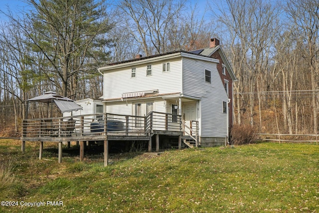 back of house featuring a yard, a chimney, and a wooden deck