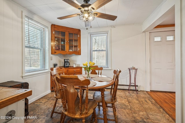 dining area featuring ceiling fan, baseboards, baseboard heating, and stone finish flooring