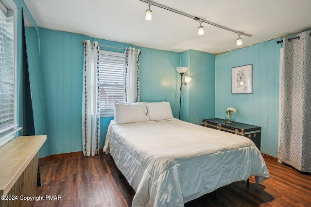 bedroom featuring baseboards, track lighting, and wood finished floors