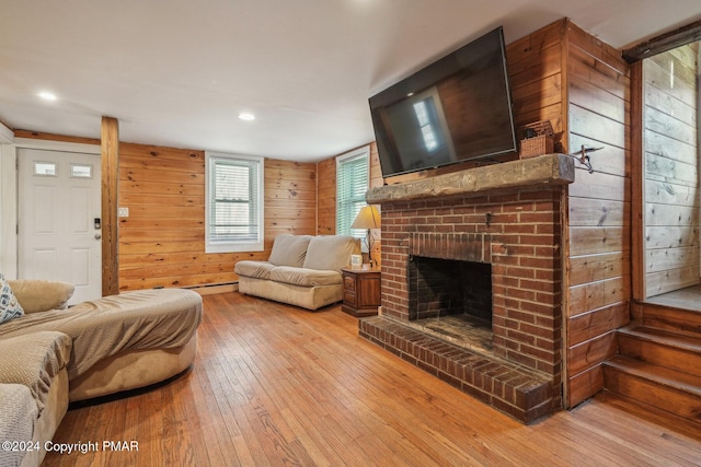 living area with a brick fireplace, wooden walls, and light wood finished floors