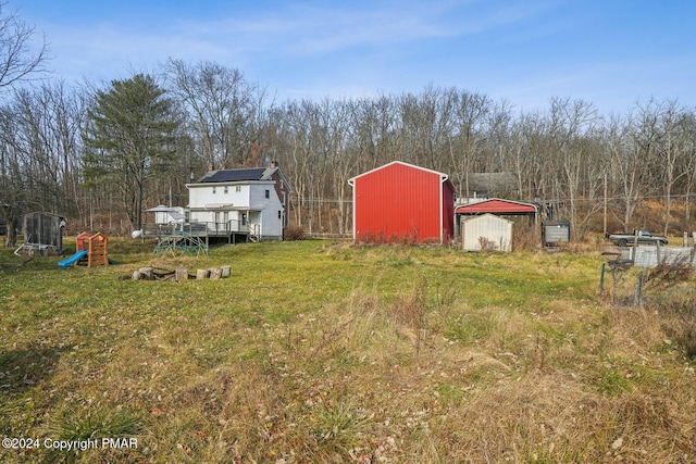 view of yard with a deck, a detached garage, and an outdoor structure