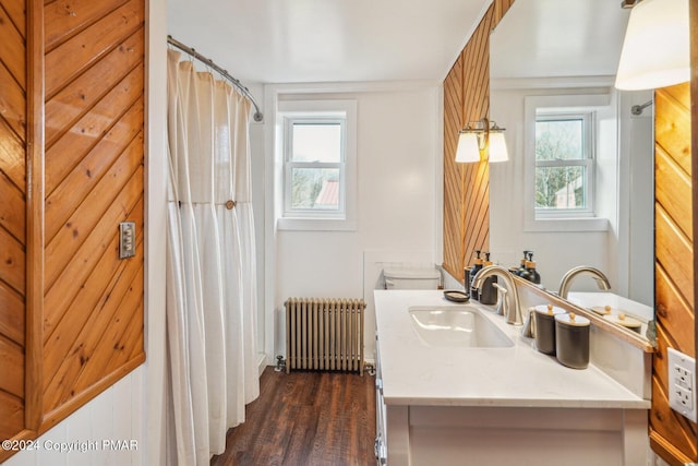 full bath with radiator, a healthy amount of sunlight, wood finished floors, and vanity