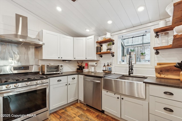 kitchen featuring open shelves, a toaster, appliances with stainless steel finishes, wall chimney exhaust hood, and a sink