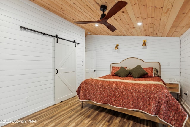 bedroom with wood finished floors, a barn door, wood walls, lofted ceiling, and wood ceiling