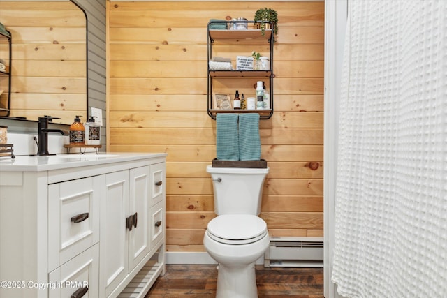 bathroom with a baseboard heating unit, hardwood / wood-style floors, and wooden walls