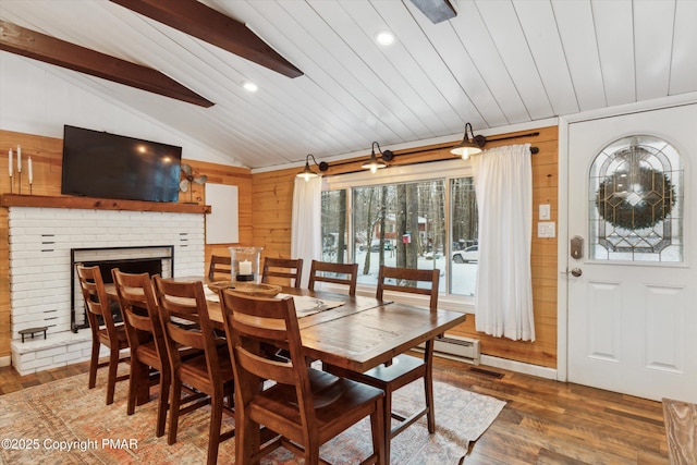 dining room with wood walls, vaulted ceiling with beams, dark hardwood / wood-style flooring, wood ceiling, and a brick fireplace