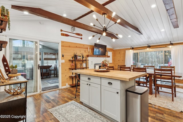 kitchen with wood counters, white cabinetry, lofted ceiling with beams, a kitchen breakfast bar, and a kitchen island