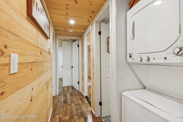 laundry room with dark wood-type flooring, stacked washer and dryer, wooden ceiling, and laundry area