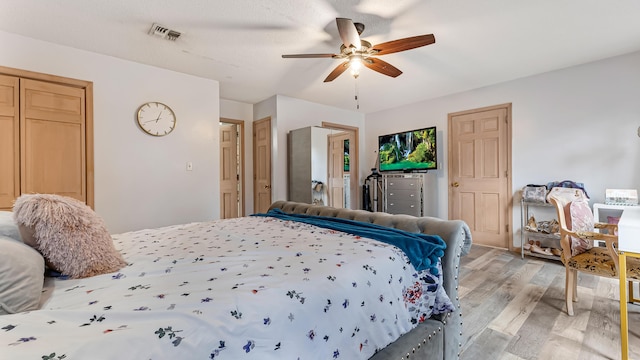 bedroom with a ceiling fan, visible vents, and light wood finished floors