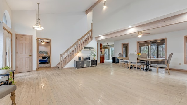 entrance foyer with stairway, a ceiling fan, light wood-style flooring, a towering ceiling, and beamed ceiling