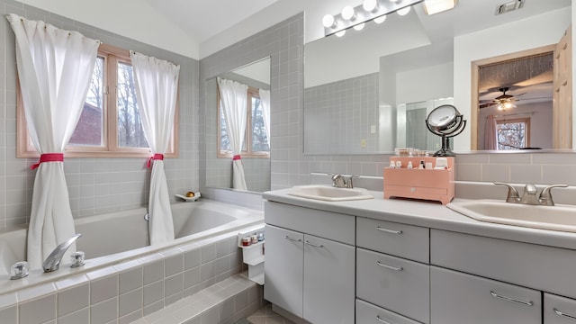 bathroom featuring tiled bath, visible vents, double vanity, and a sink