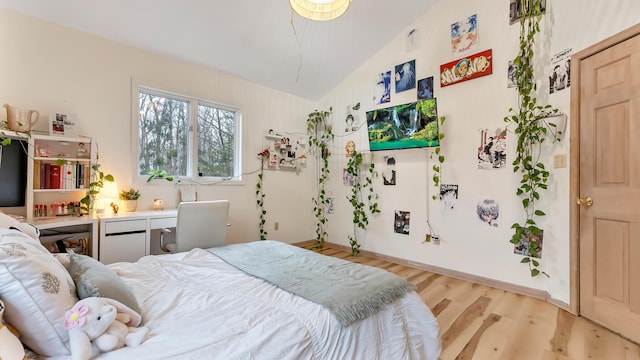 bedroom featuring baseboards, light wood-type flooring, and lofted ceiling