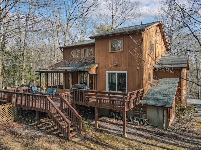 rear view of property featuring roof with shingles, a deck, and stairs