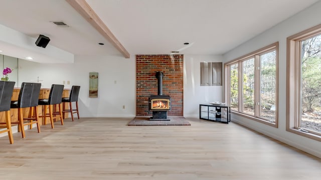 living room featuring a wealth of natural light, beamed ceiling, and wood finished floors