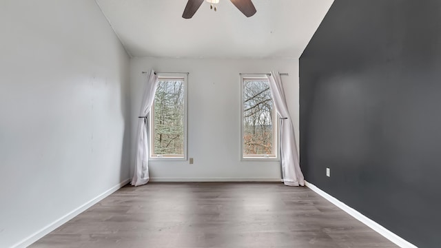 unfurnished room featuring a ceiling fan, wood finished floors, and baseboards