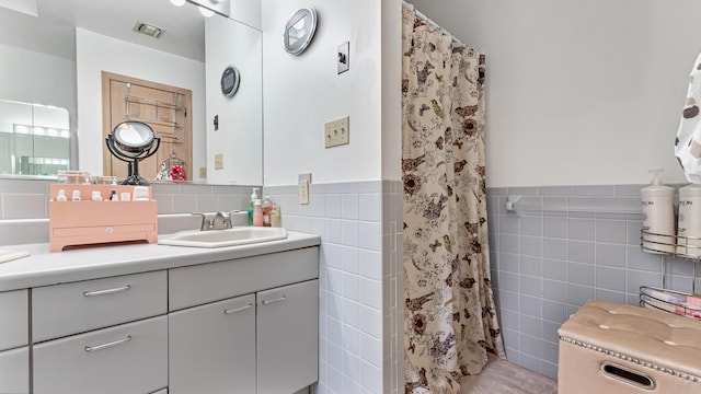 bathroom with a wainscoted wall, visible vents, a shower with curtain, tile walls, and vanity