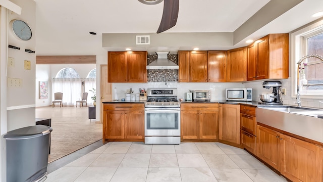 kitchen featuring wall chimney exhaust hood, visible vents, appliances with stainless steel finishes, and plenty of natural light