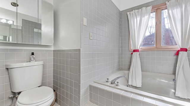 full bathroom featuring tiled bath, toilet, and tile walls