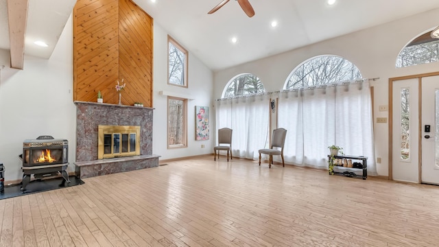 sitting room with wood-type flooring, high vaulted ceiling, ceiling fan, and a fireplace