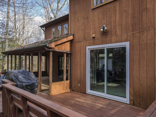 wooden deck with a sunroom and a grill