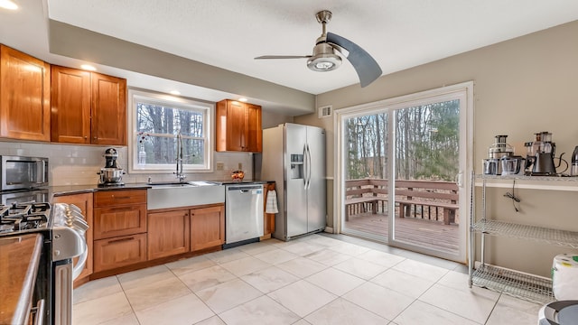 kitchen with plenty of natural light, tasteful backsplash, appliances with stainless steel finishes, and brown cabinetry