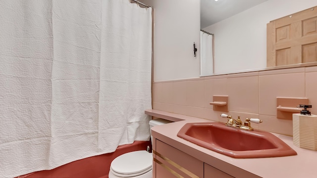 full bathroom featuring tile walls, wainscoting, toilet, and vanity