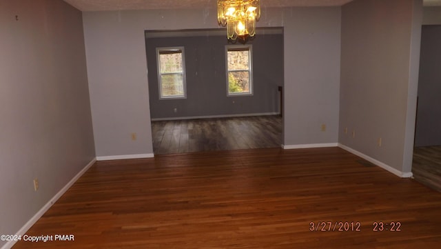 empty room featuring dark hardwood / wood-style floors and a chandelier