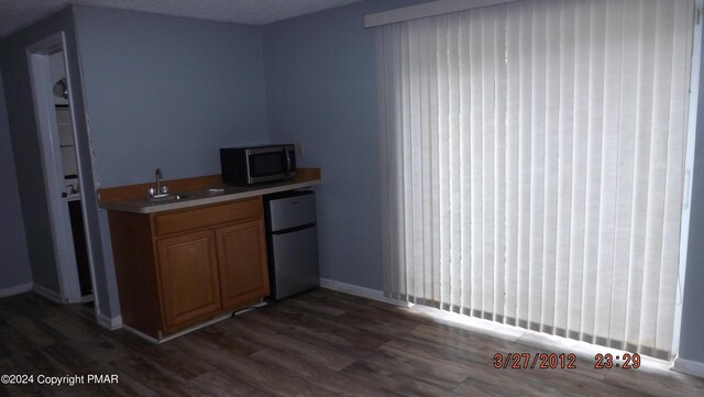 bar featuring dark hardwood / wood-style flooring, refrigerator, and sink