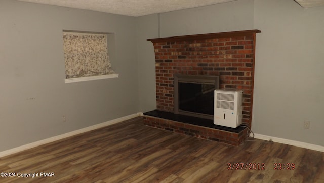 unfurnished living room with dark hardwood / wood-style flooring, a brick fireplace, and a textured ceiling