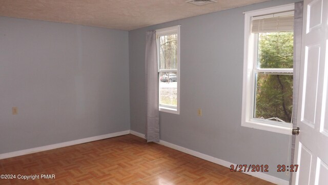 spare room with light parquet flooring and a textured ceiling